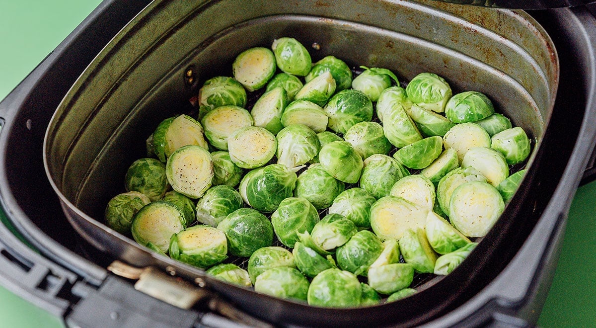 Brussels sprouts in an air fryer on a green background.
