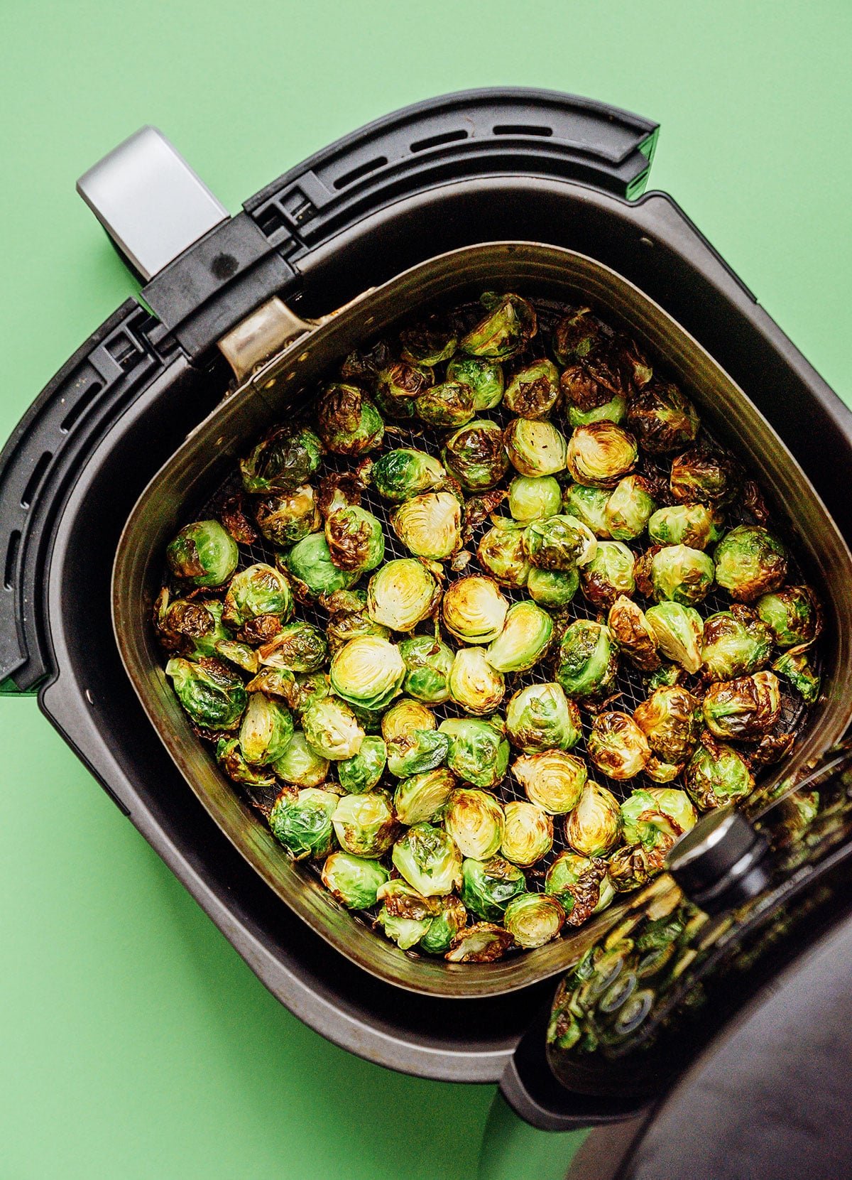 Brussels sprouts in an air fryer on a green background.