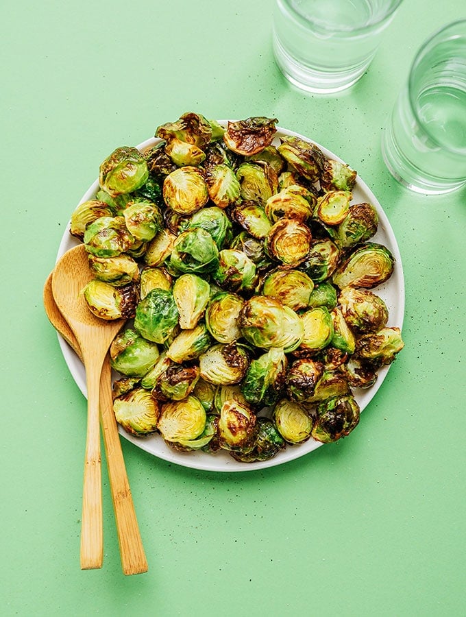 Air fried brussels sprouts in a bowl with green background
