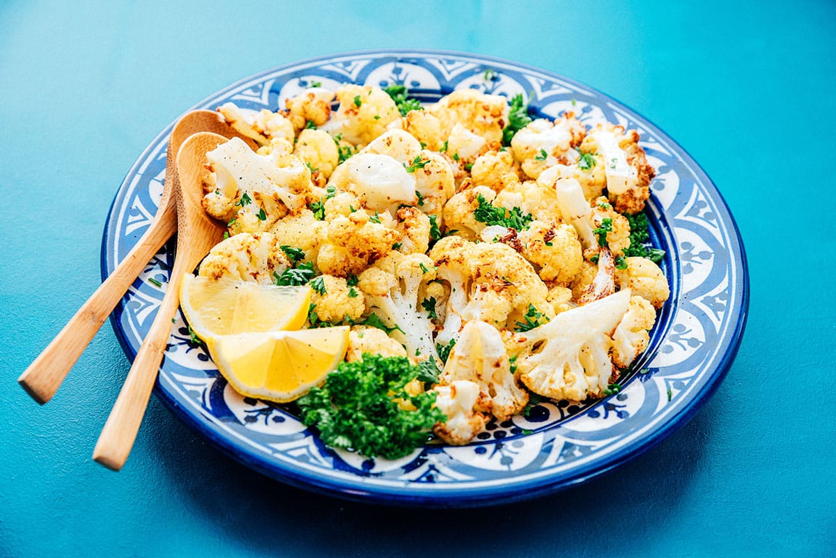 Air fryer cauliflower on a blue plate with wooden spoons.