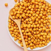 Plate full of crispy chickpeas with a wooden spoon.