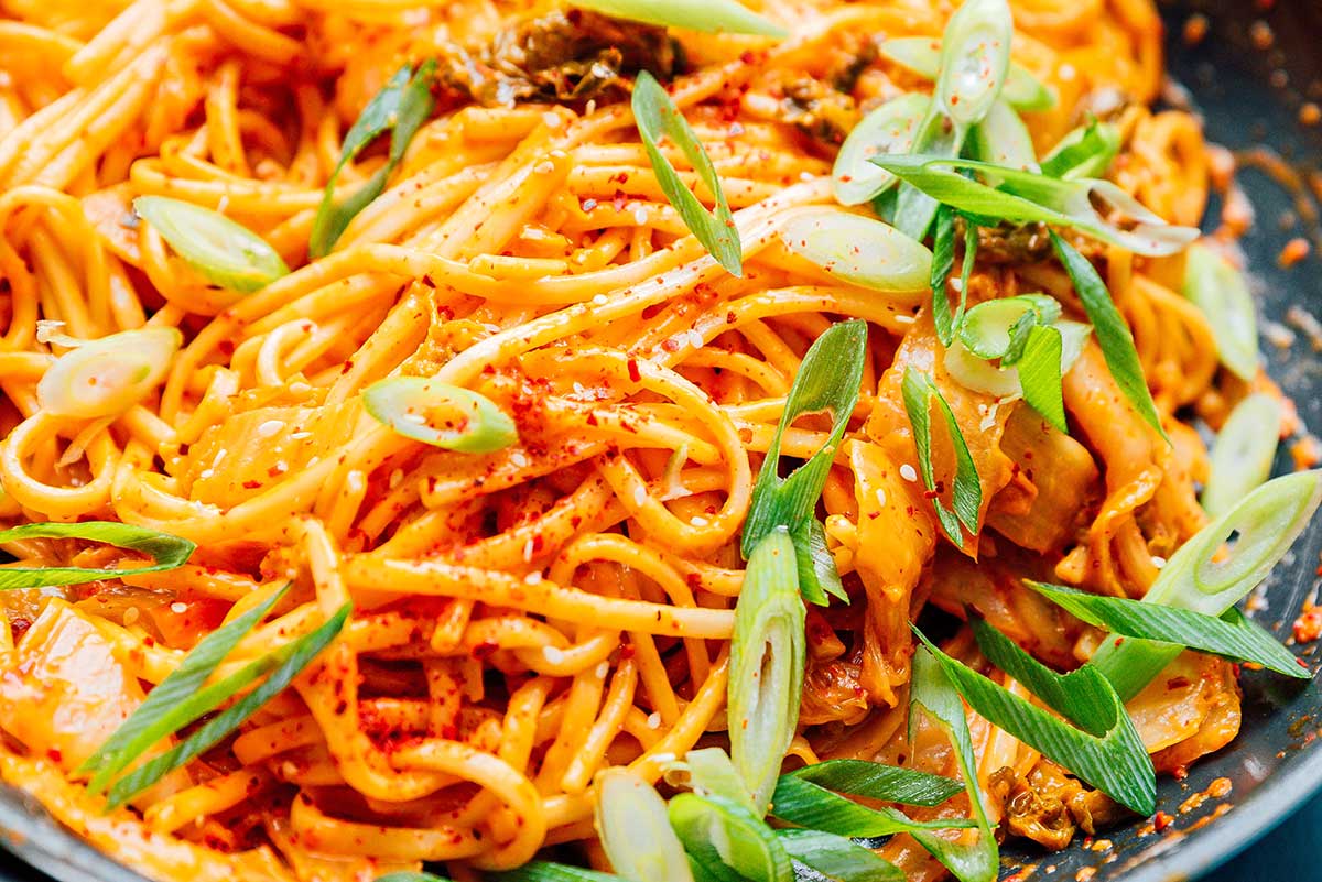 Up close image of kimchi udon noodles topped with green onions