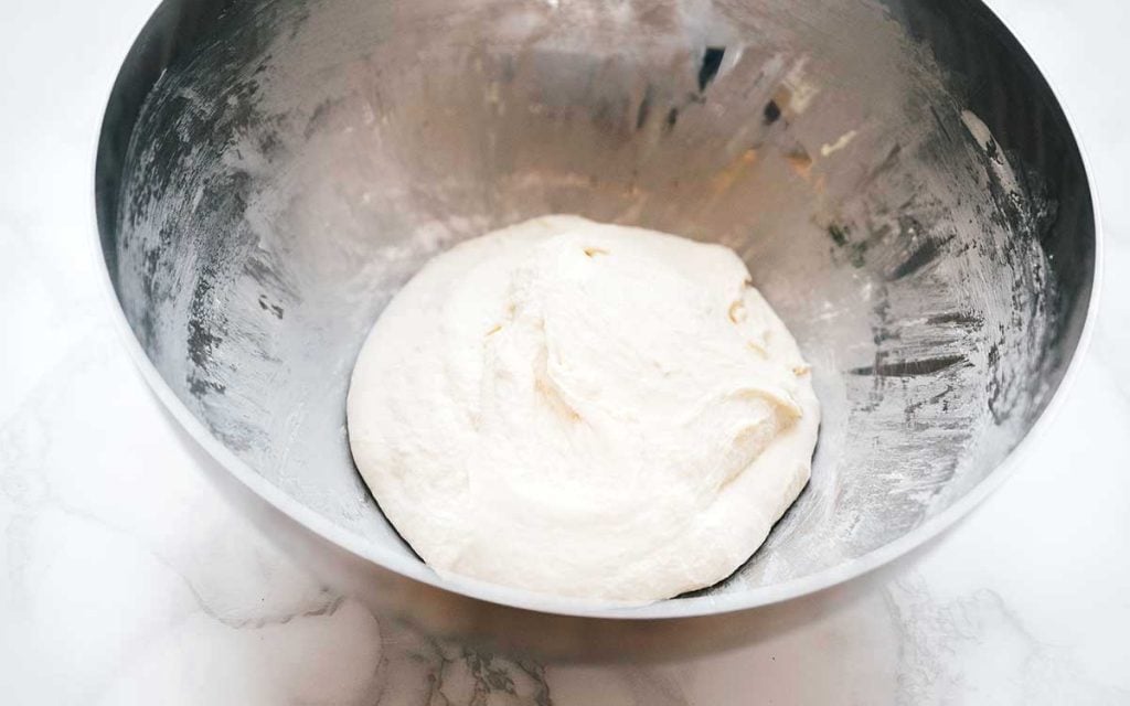Naan dough in a bowl on a white background