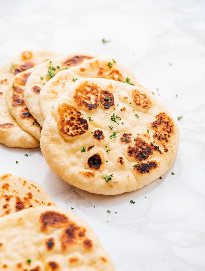 Naan bread slices stacked on a white background