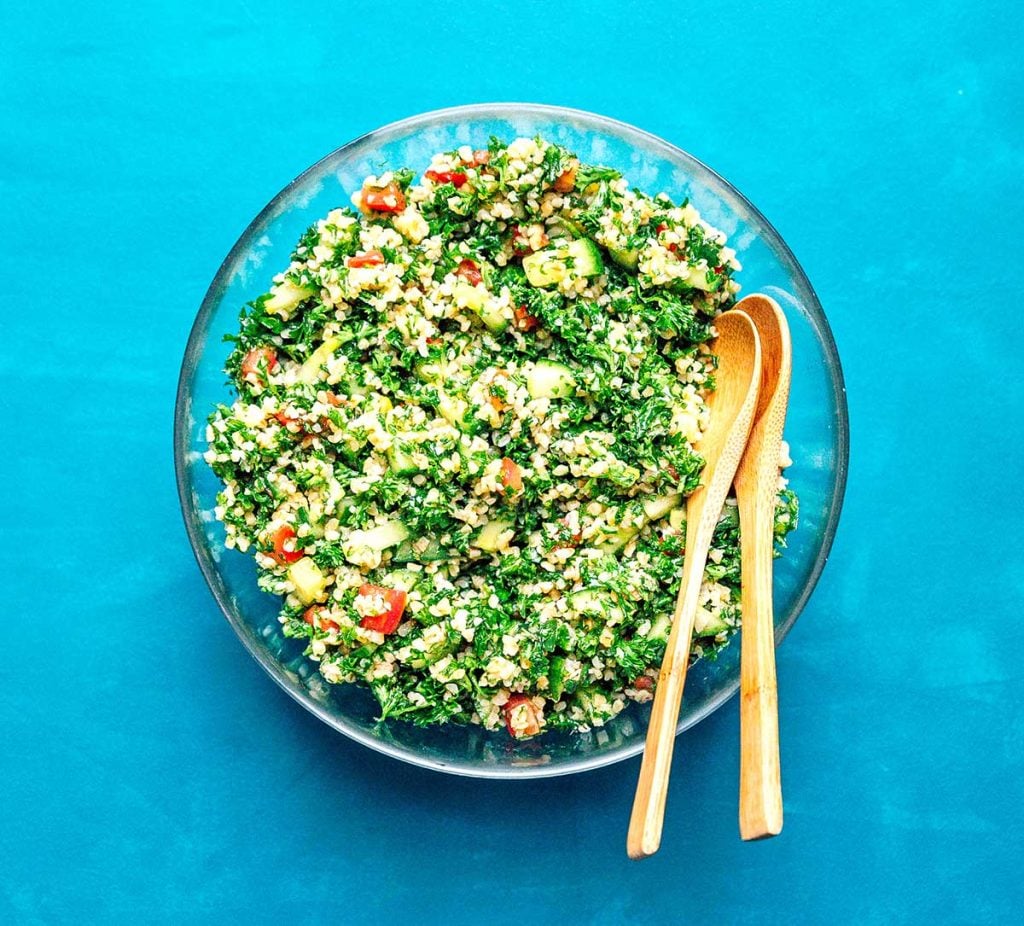 Bird's eye view of a large bowl of tabbouleh salad on a blue background
