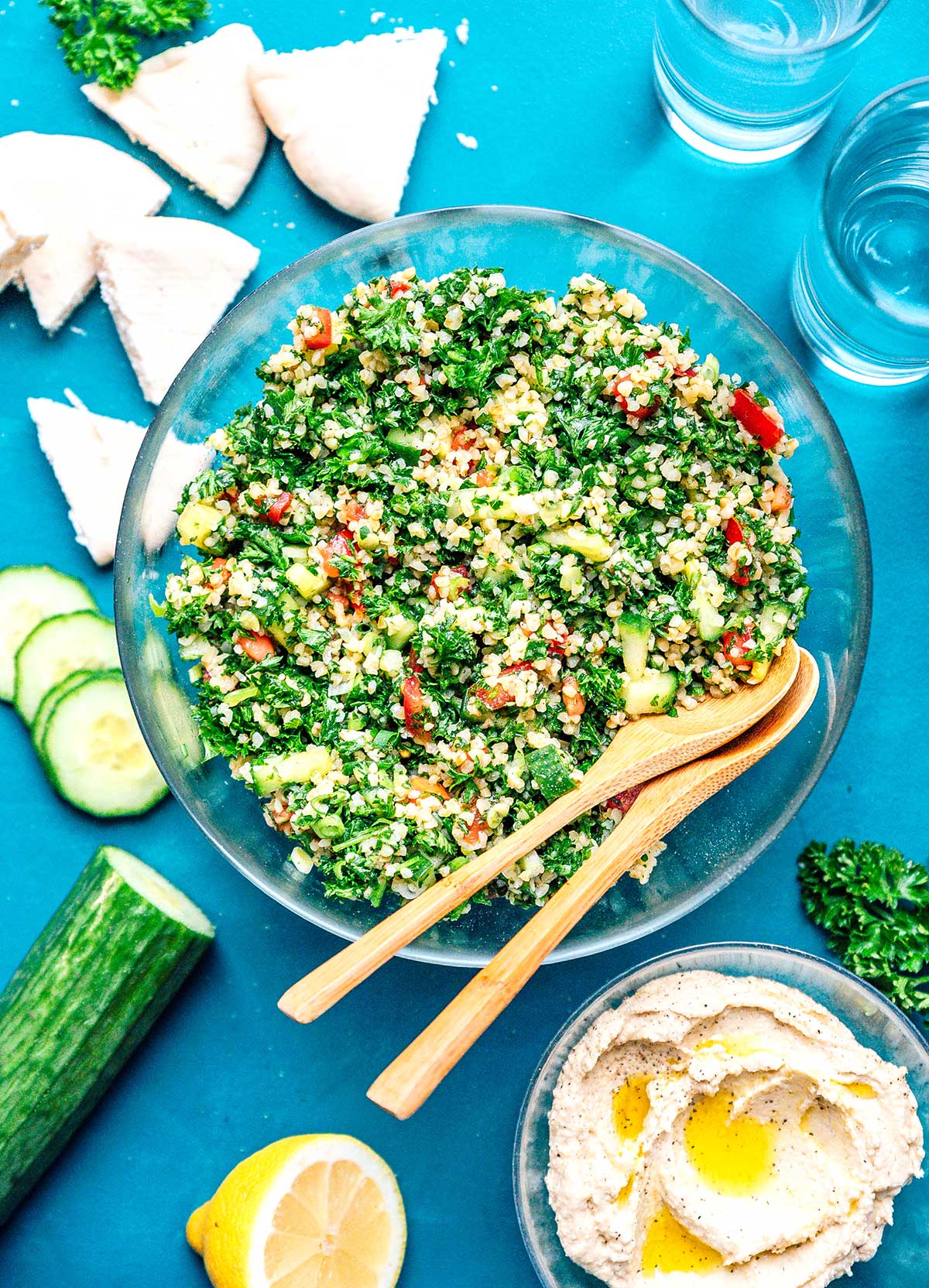 Bird's eye view of a large bowl of tabbouleh salad with various ingredients laid out around the bowl