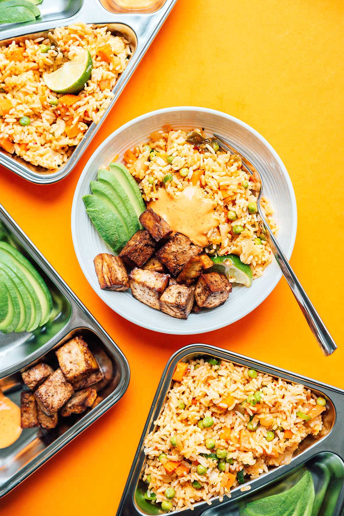 Kimchi fried rice meal prep in various bowls and containers on a yellow background
