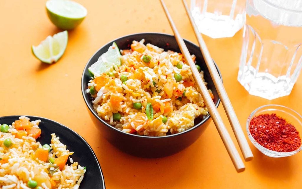 Two bowls of kimchi fried rice on an orange background