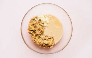 A bowl with mashed bananas, melted butter, and sugar mixed together sits on a light surface, reminiscent of the rich texture found in dishes like baba ganoush.