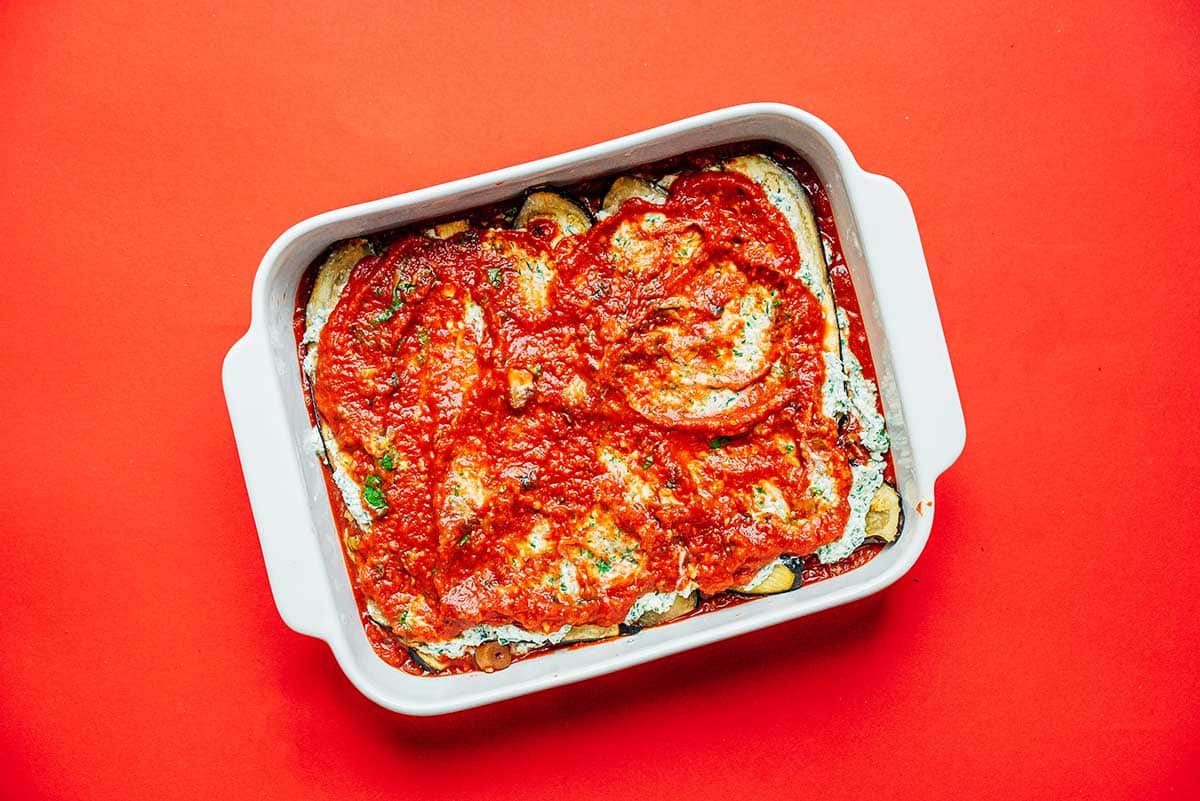 A casserole dish filled with sauce, eggplant, and ricotta layers