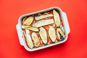 Layering eggplant lasagna into a pan.