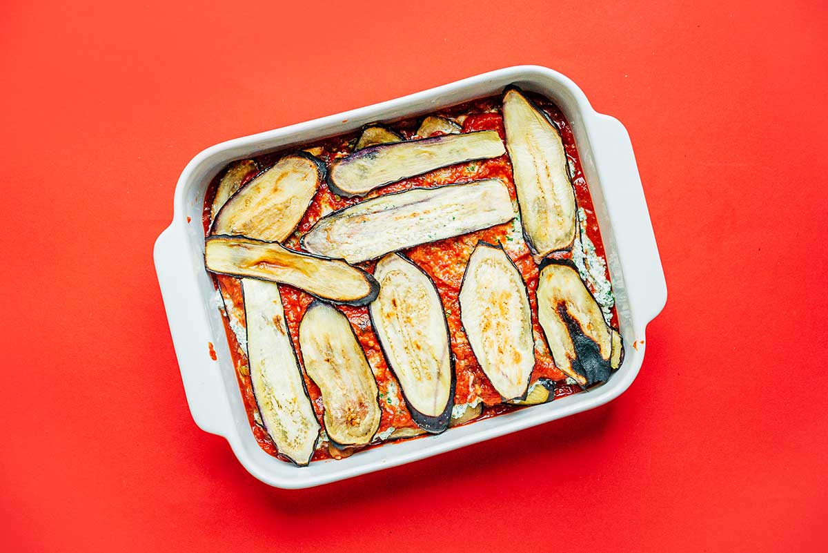 A casserole dish filled with sauce, eggplant, and ricotta layers