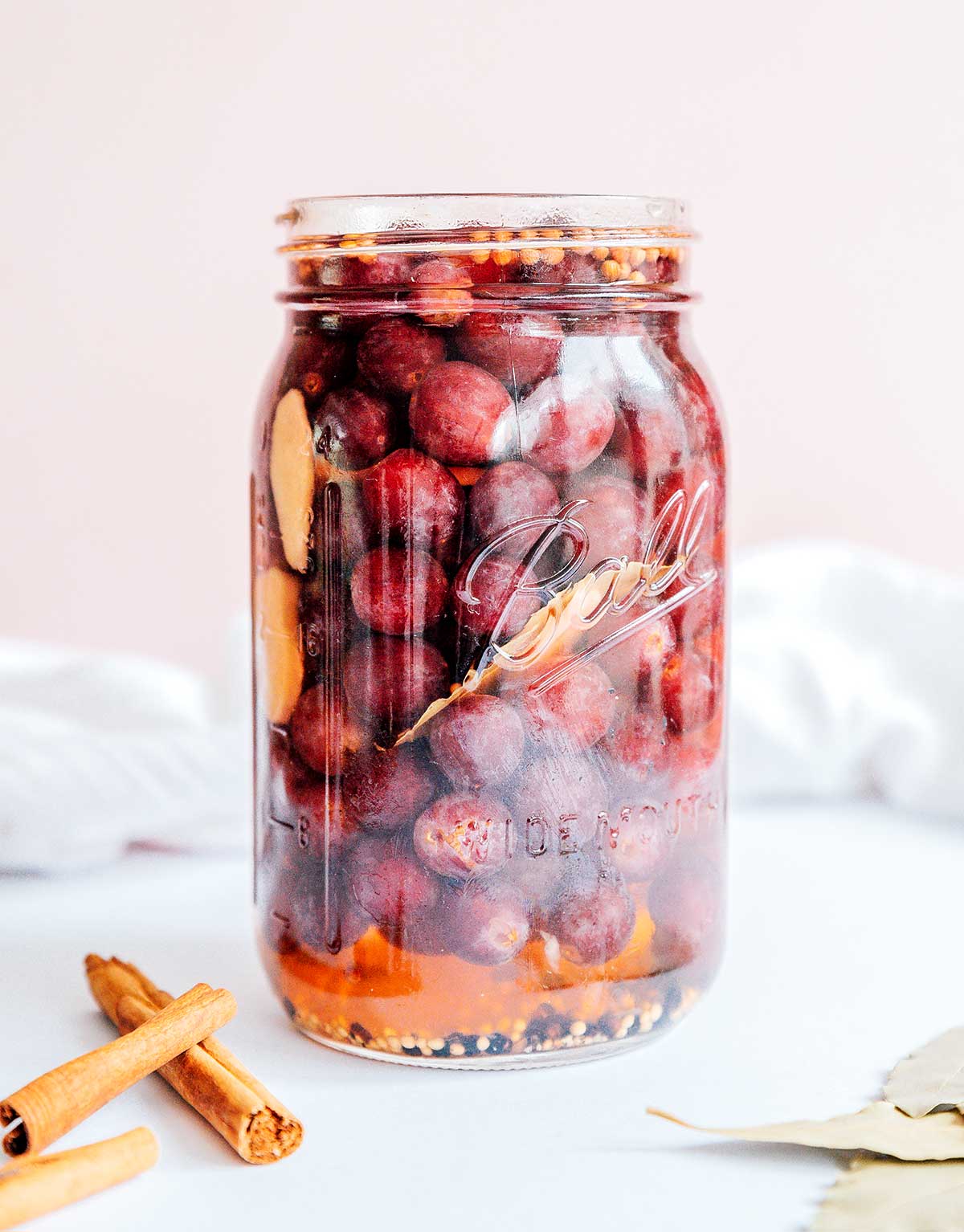 A mason jar filled with quick pickled grapes in their spiced liquid mixture