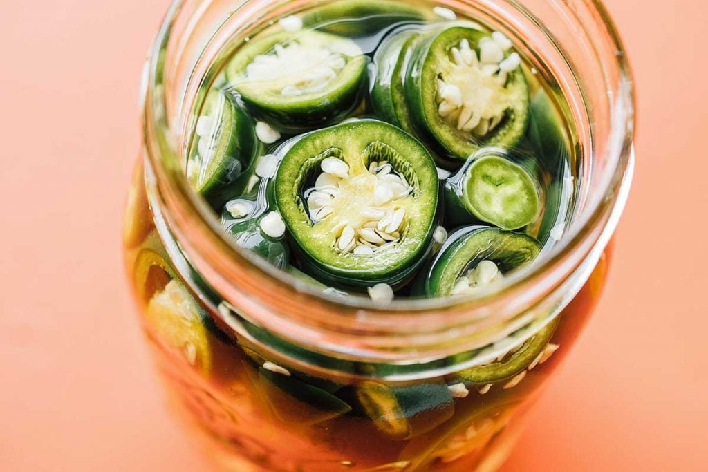 A top view of a mason jar filled with pickled jalapeños