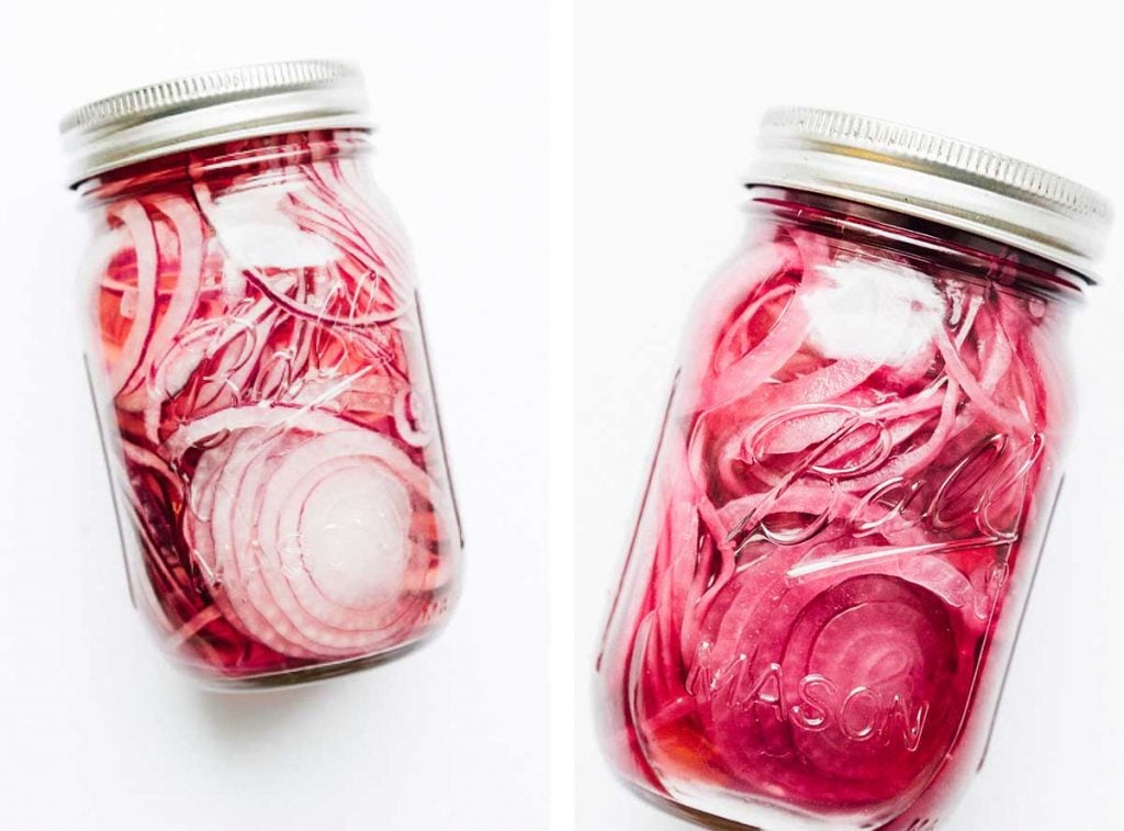 Two mason jars lying on their sides filled with quick pickled red onions