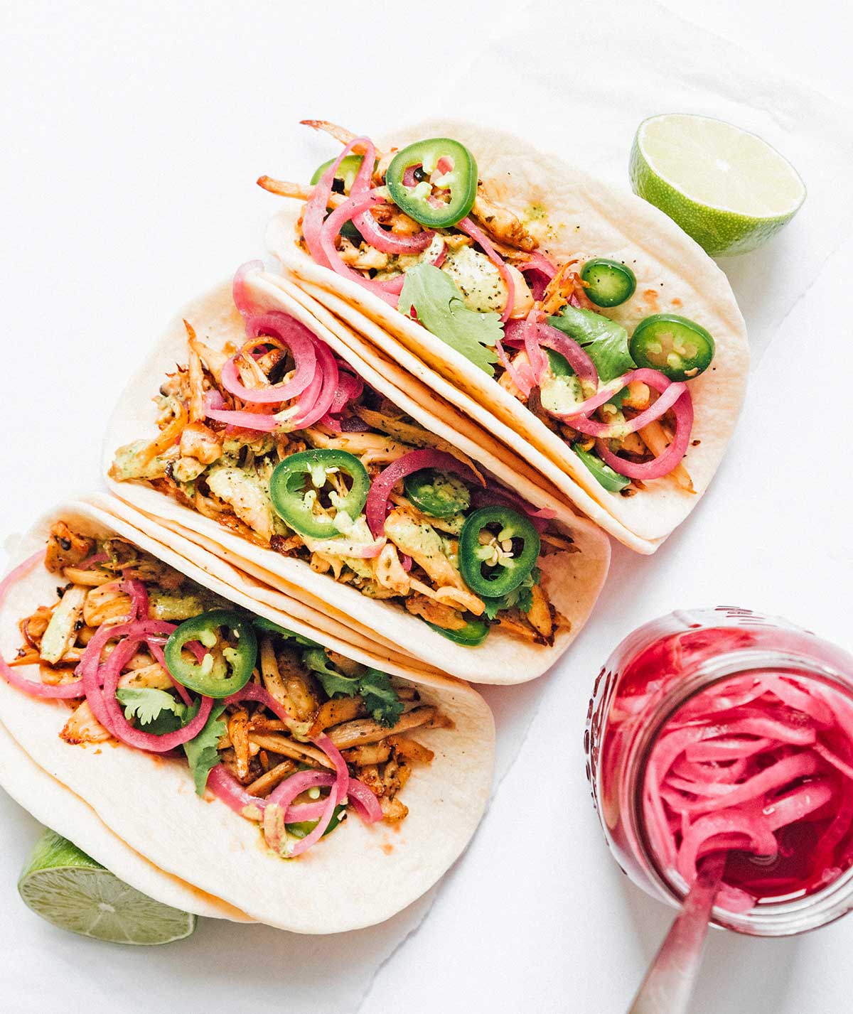 Three tacos, a mason jar of quick pickled red onions, and two lime halves