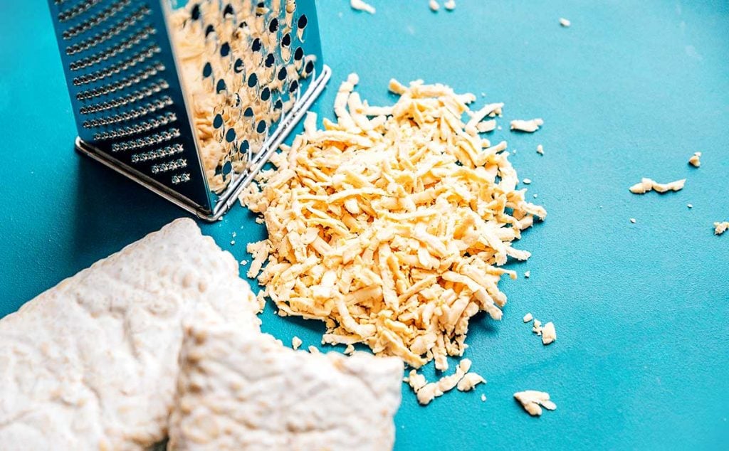 A pile of romano cheese next to a cheese grater