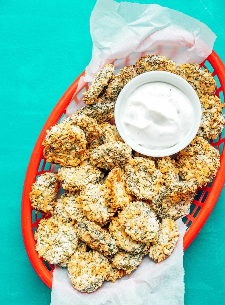 A red basket filled with air fryer fried pickles and paired with a creamy dipping sauce