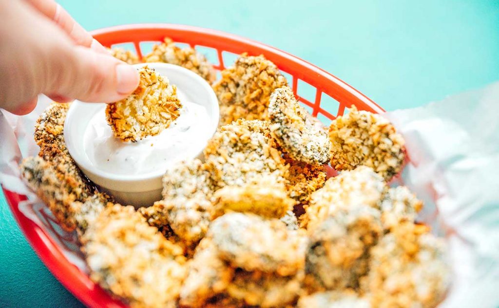 Dipping an air fryer fried pickle into a creamy dipping sauce