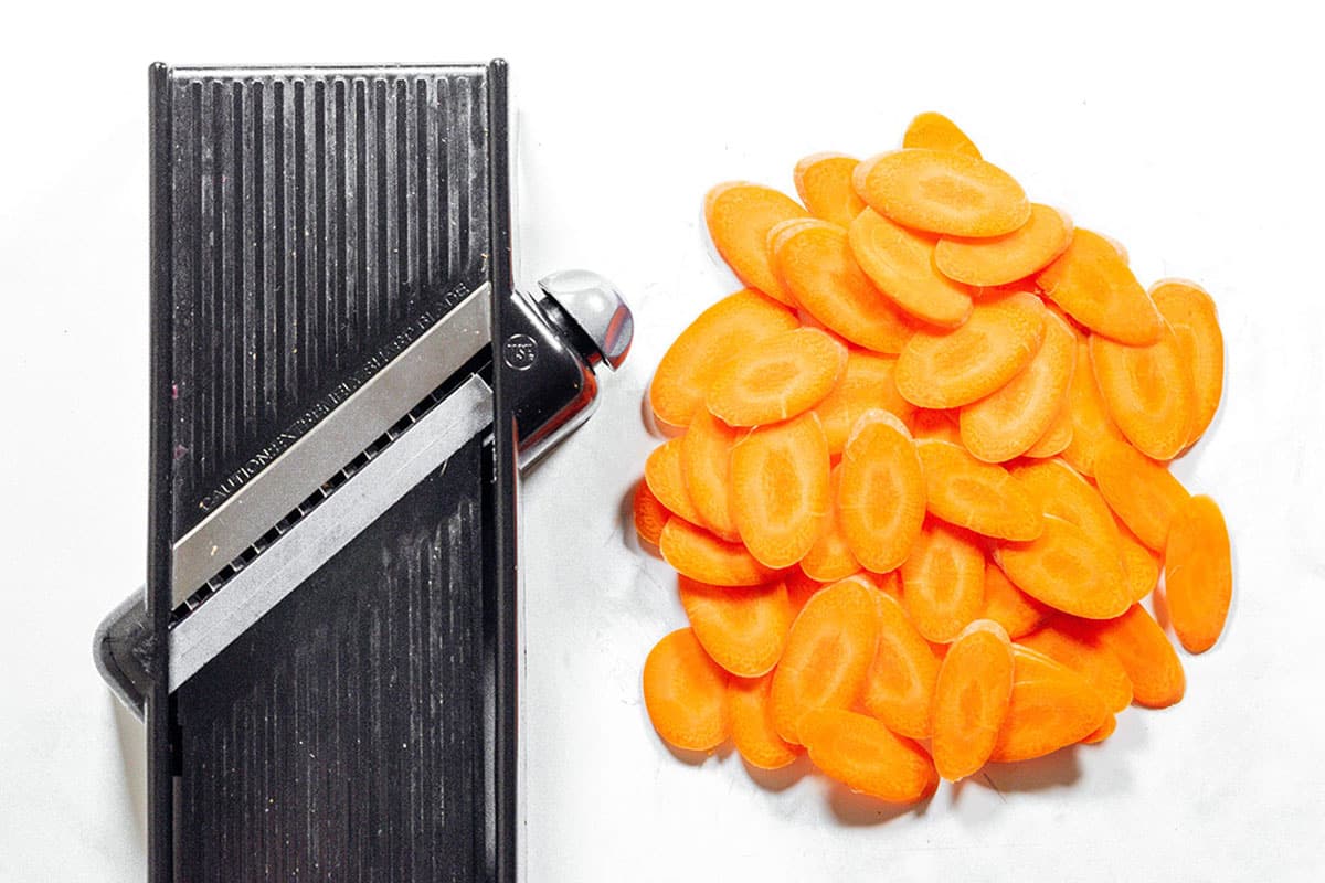 Cutting carrots thinly using a mandoline.