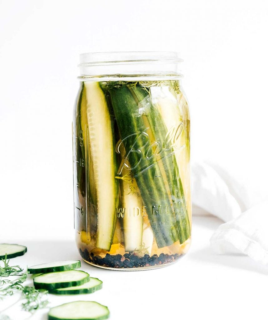 A mason jar filled with cucumber wedges and a water and vinegar pickling mixture