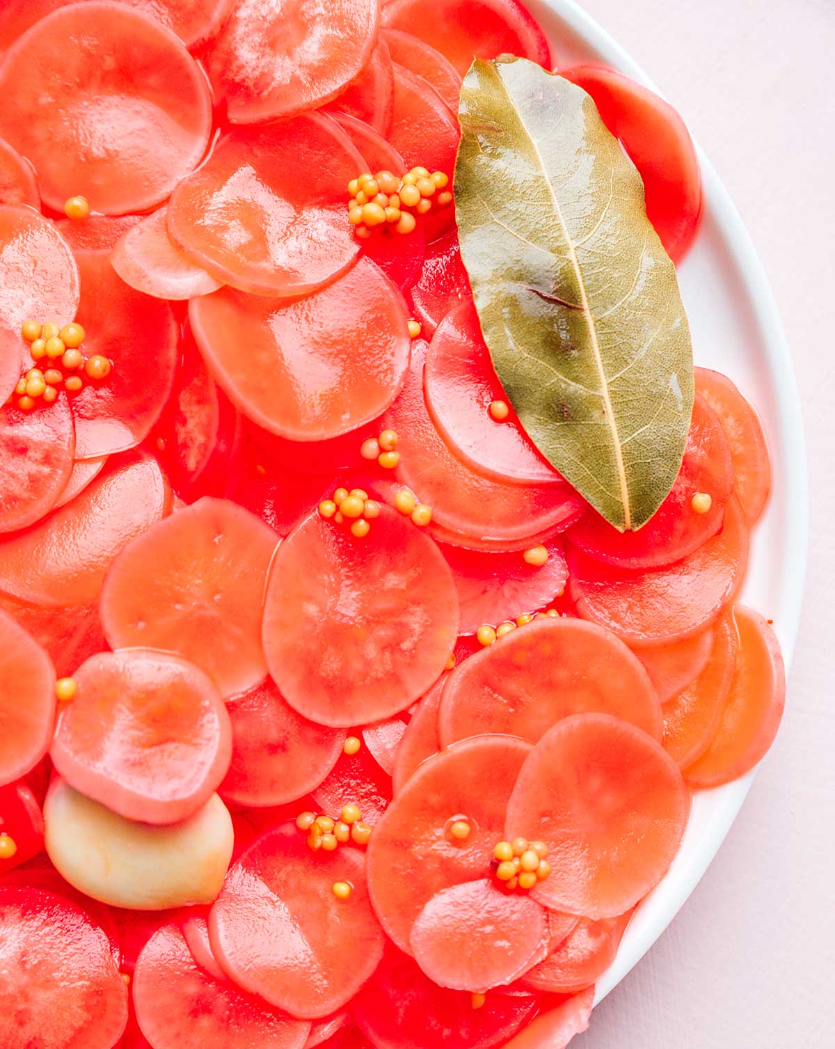 A close-up view of a white plate filled with pickled radish slices 