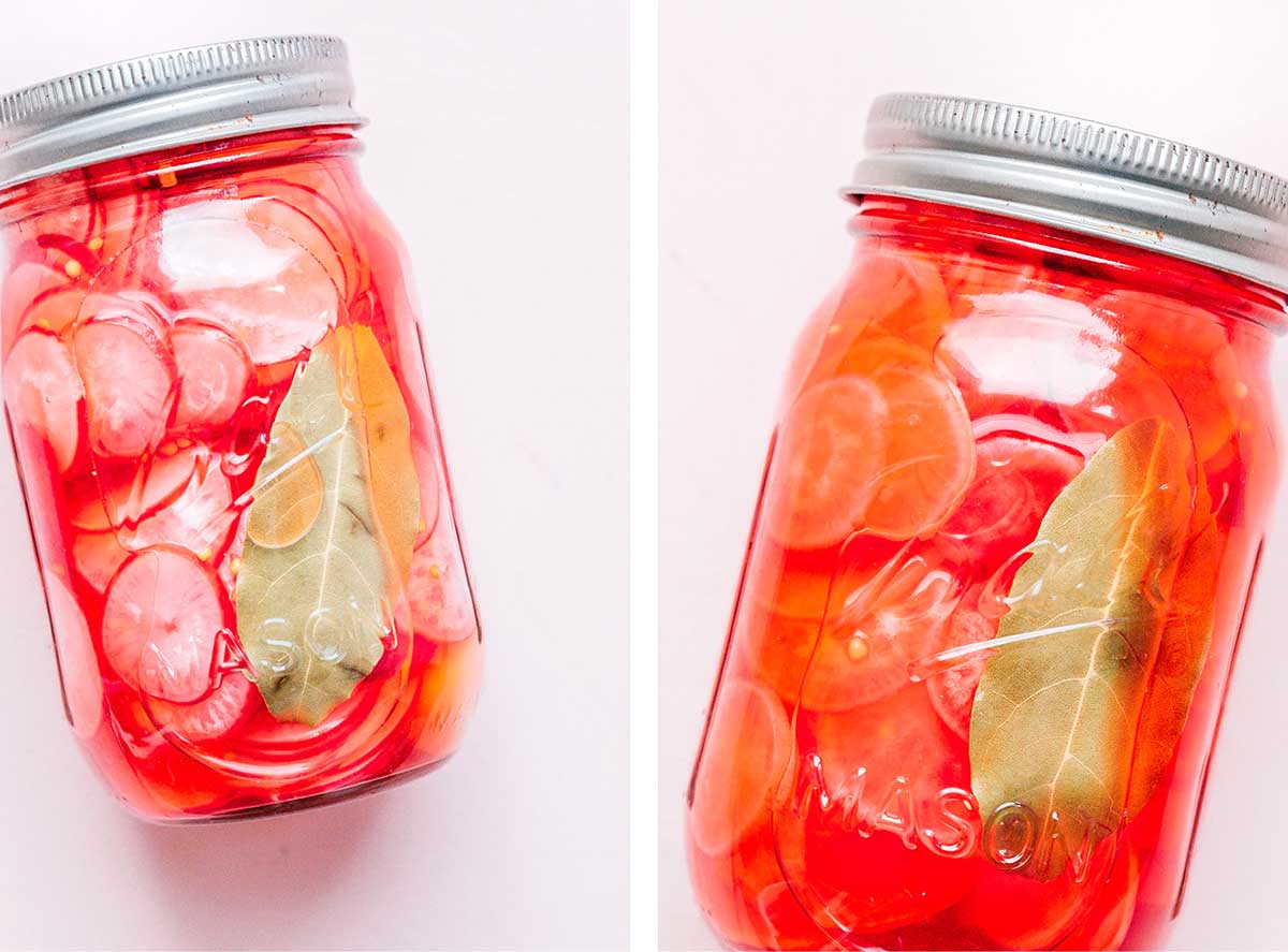 Two 16-oz mason jars filled with pickled radish slices and a hot water and vinegar liquid mixture