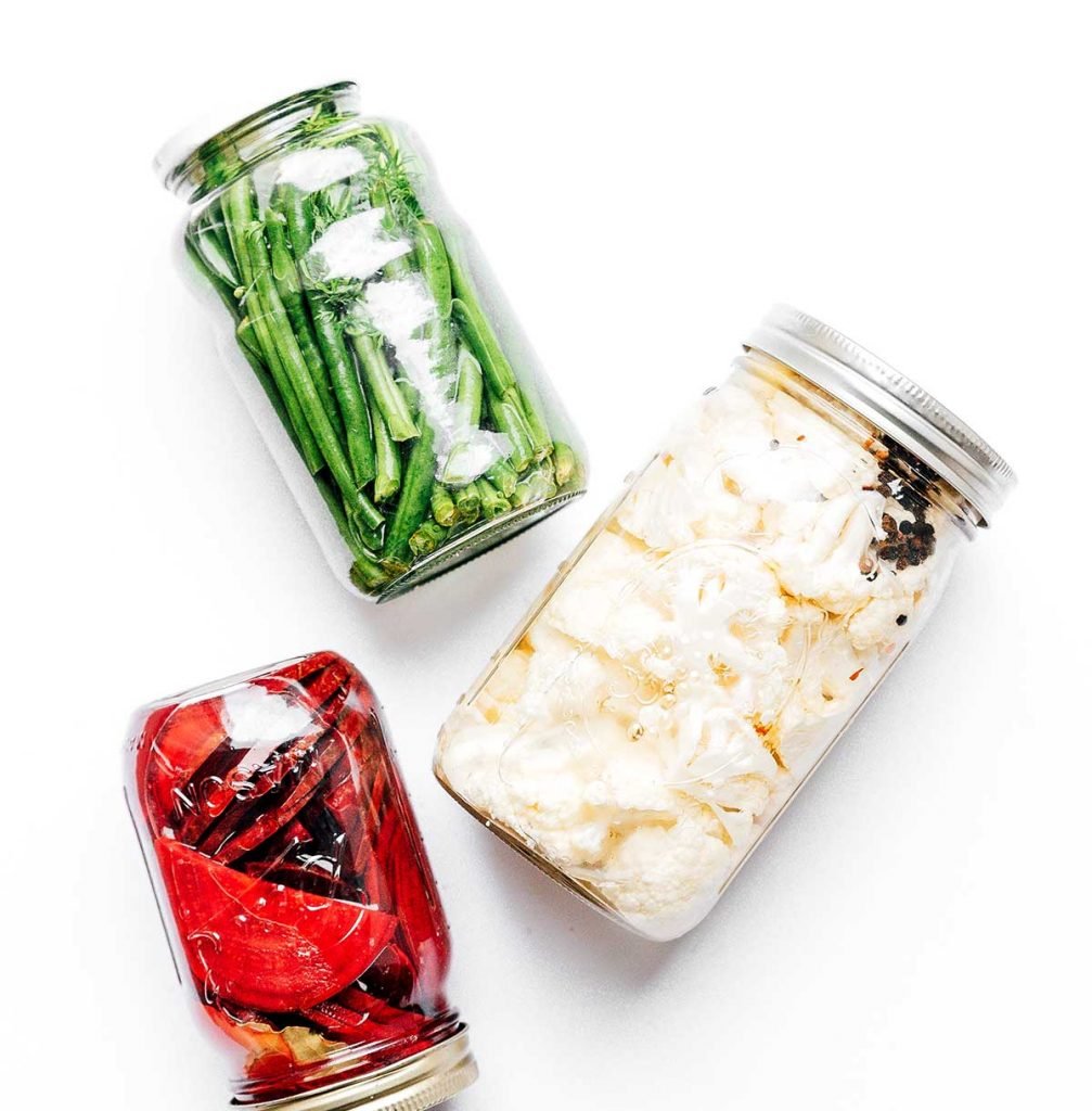 Pickled vegetables in mason jars on a white background