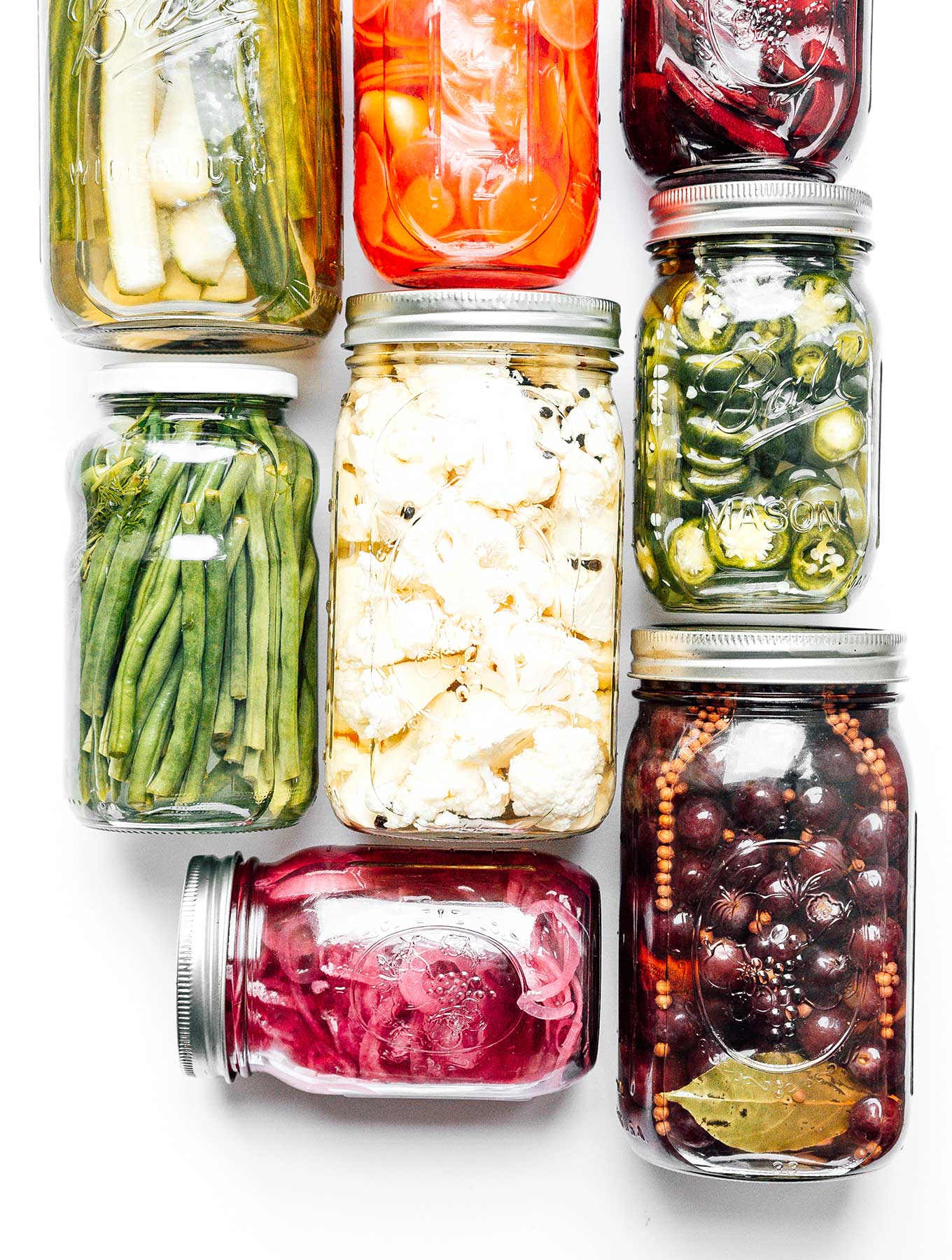Pickled vegetables in mason jars on a white background