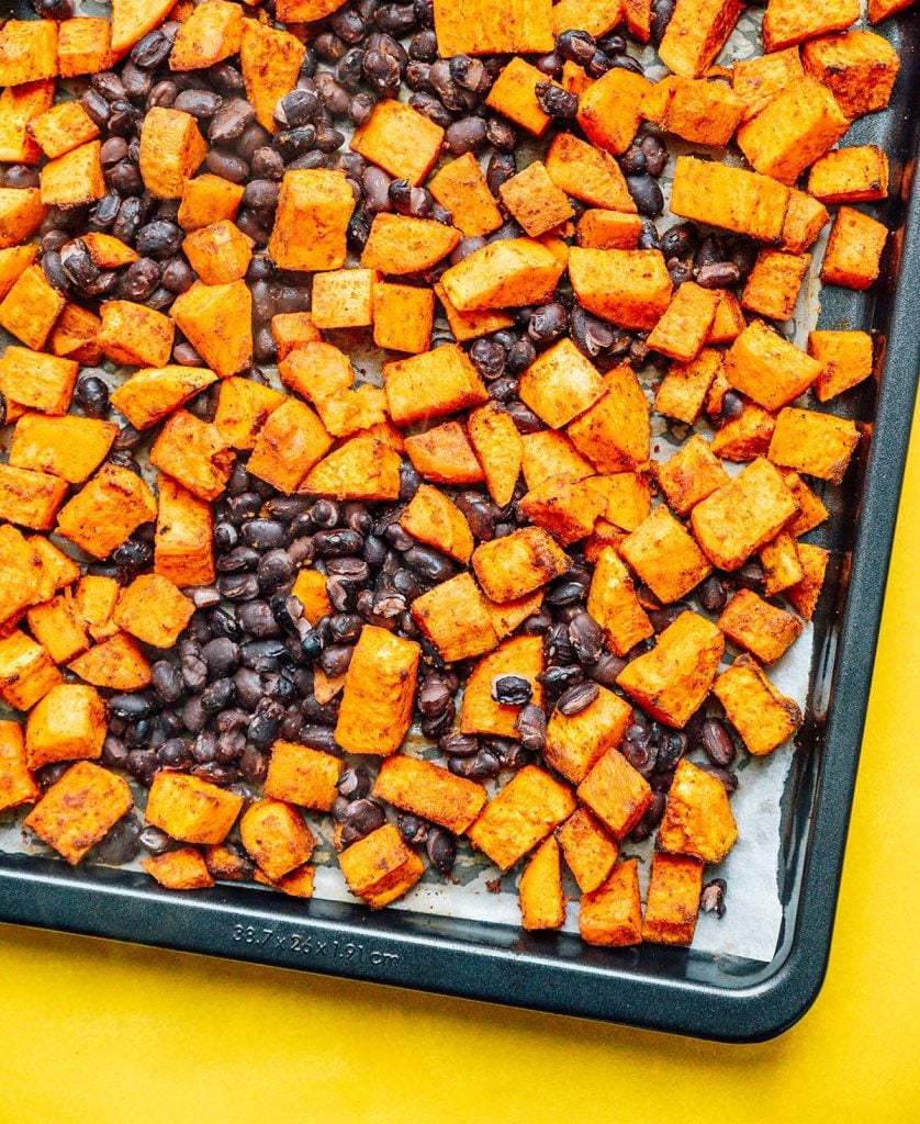 Roasted sweet potato cubes and black beans line a baking sheet