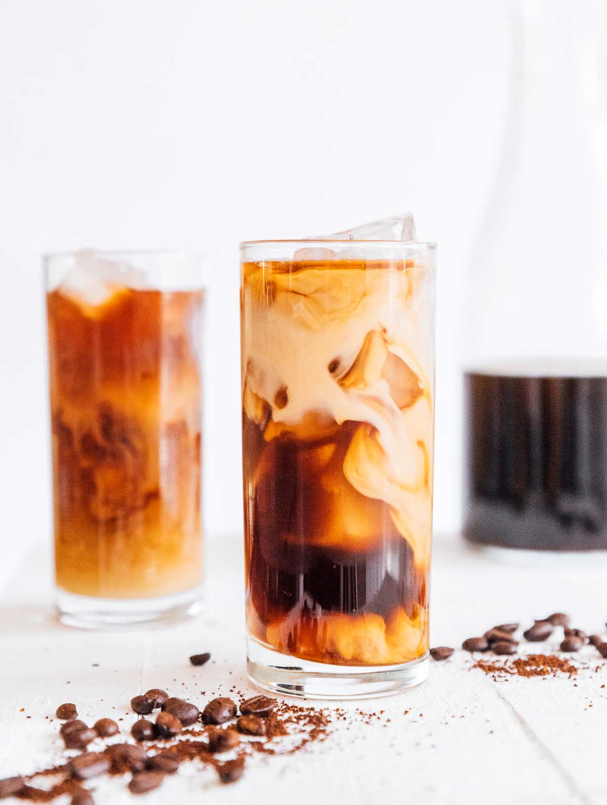 Two tall glasses of iced cold brew coffee with cream