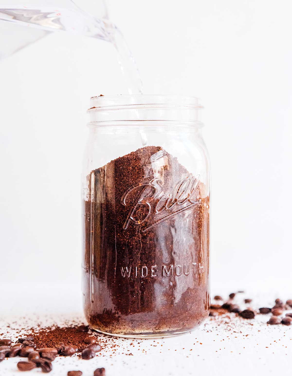 Pouring water into a mason jar filled with coffee grounds