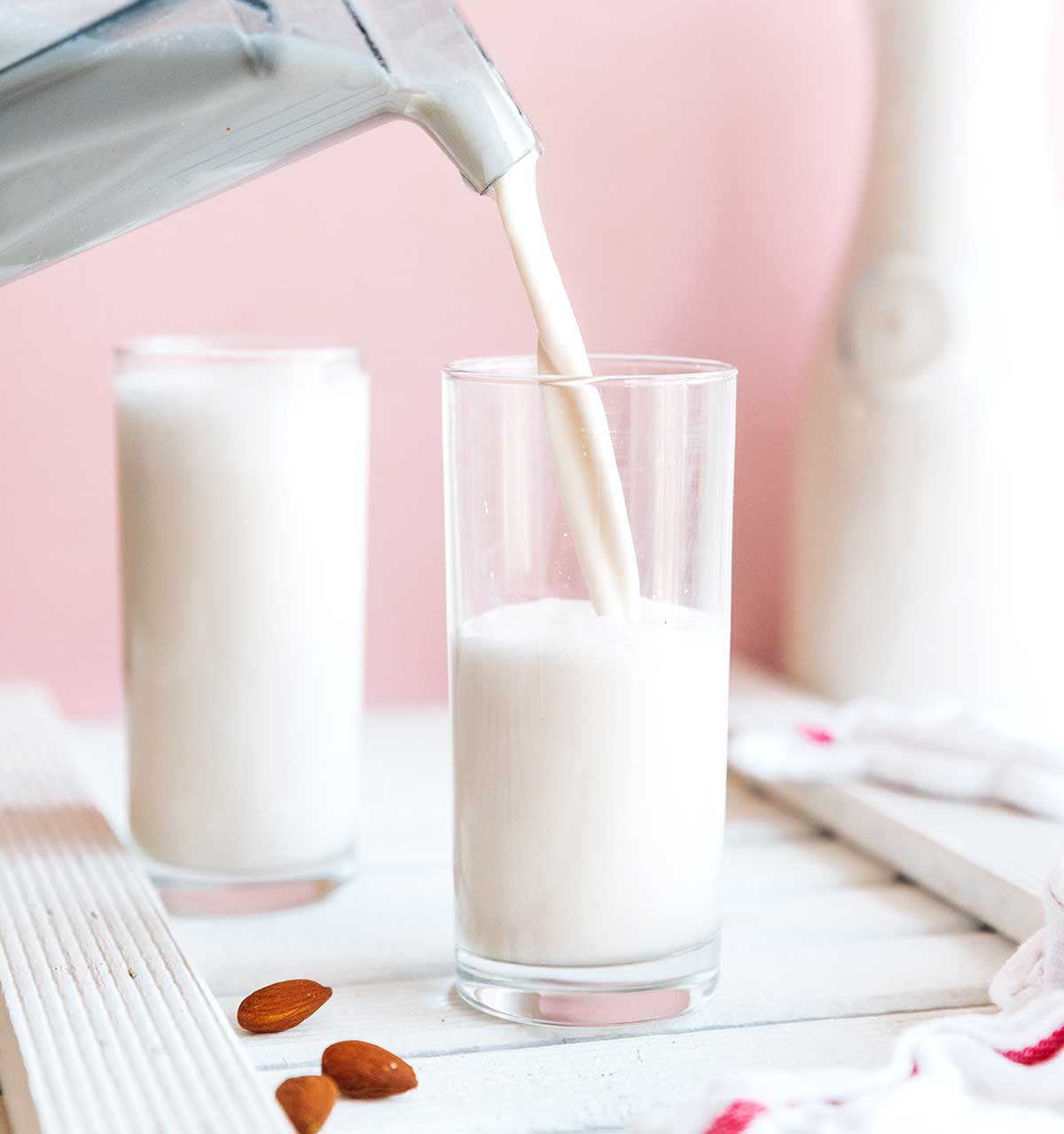 Pouring almond milk from a blender into a glass