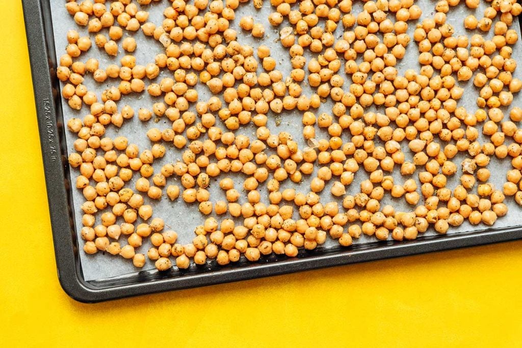 A sheet pan filled with a single layer of uncooked chickpeas