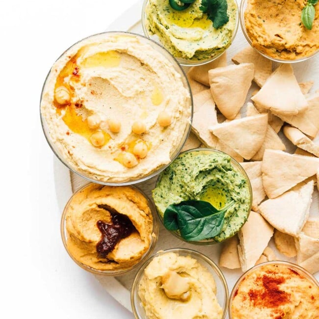 Rainbow variety of hummus in bowls on a white background