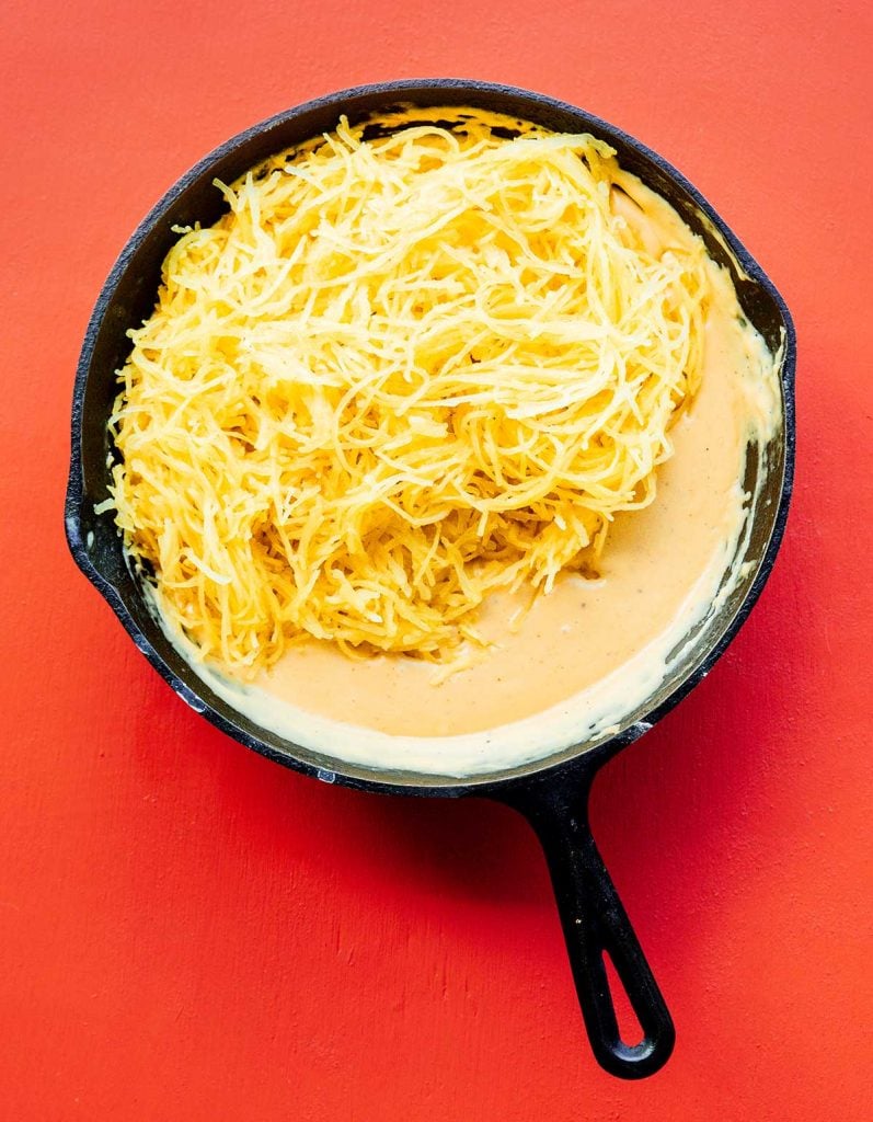 A sauté pan filled with cheese ingredients and spaghetti squash "noodles"
