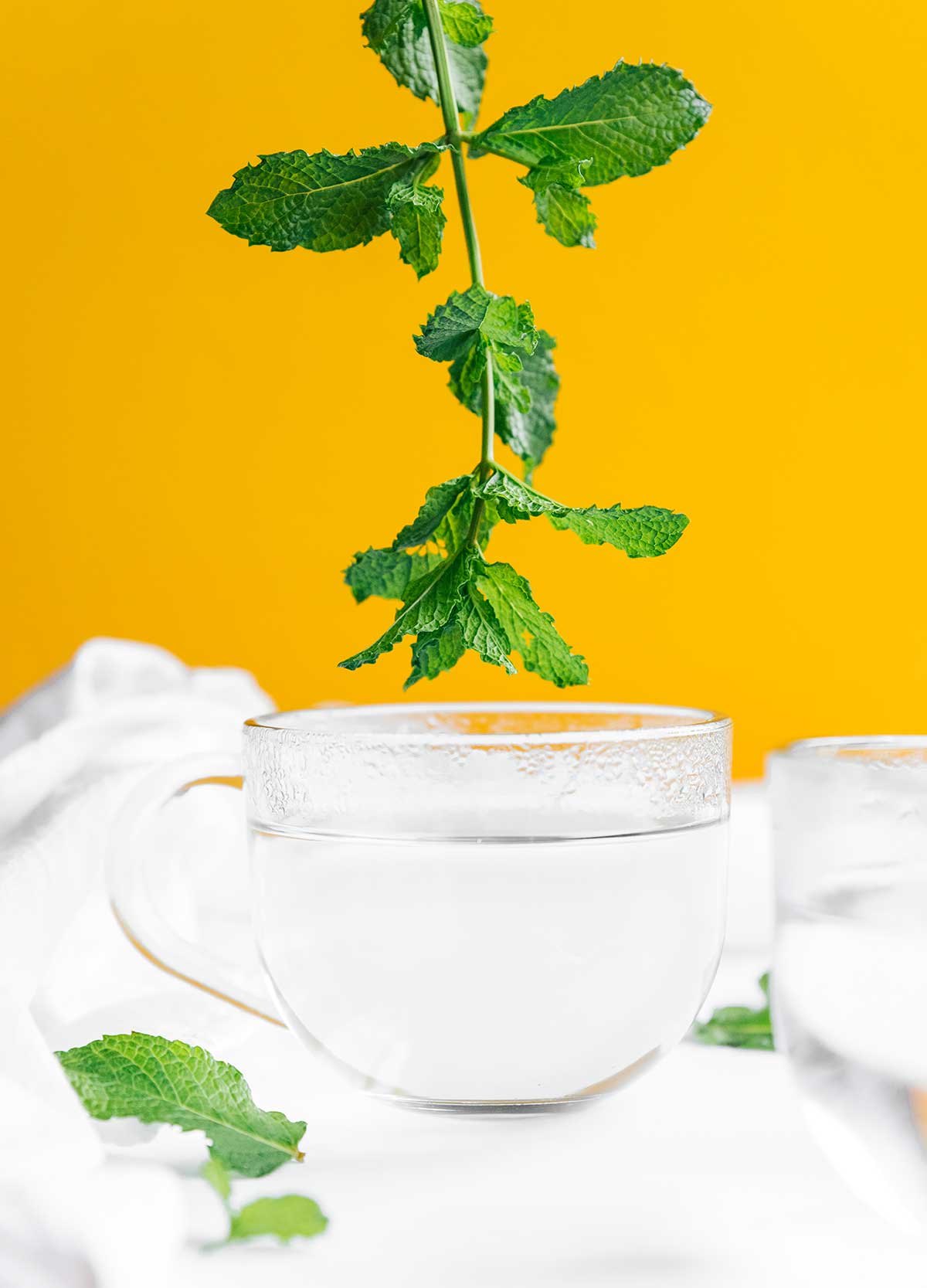Adding fresh mint to a glass of hot water