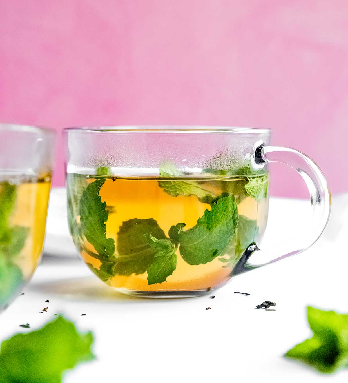 Fresh mint tea to a glass on a pink background
