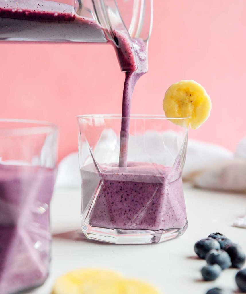 Pouring blueberry banana smoothie from a blender into a glass