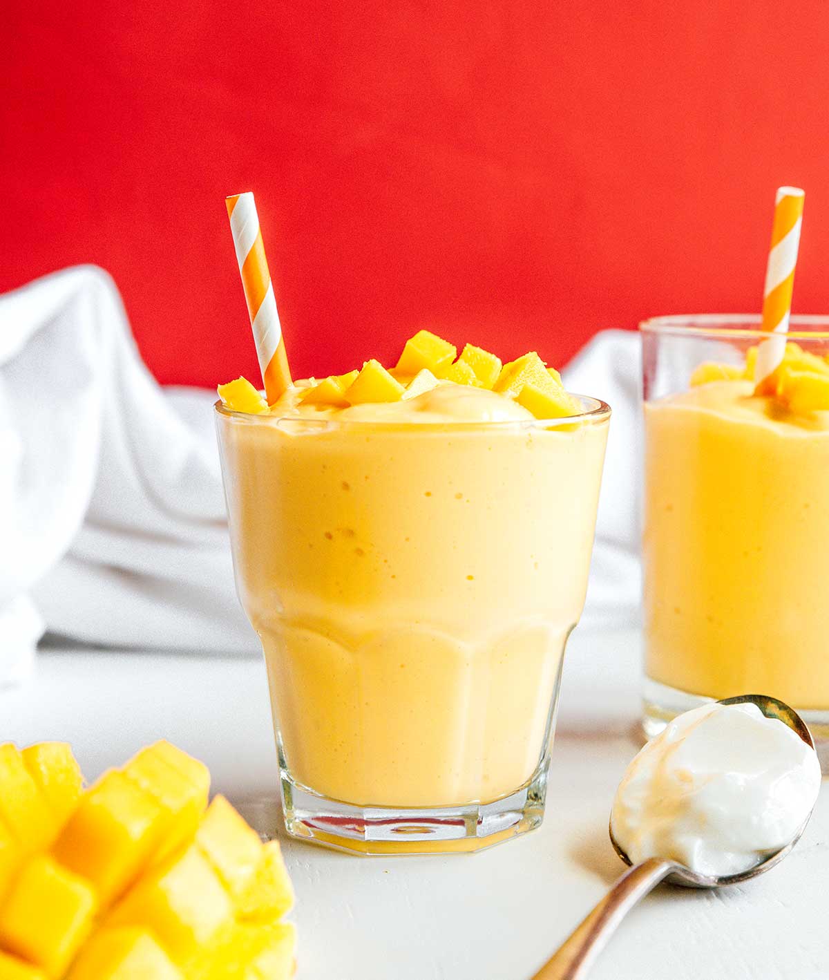 A glass filled with mango smoothie and topped with diced mangos