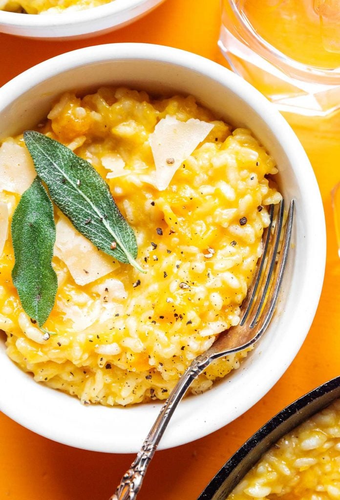 A white bowl filled with butternut squash risotto and topped with butter and sage