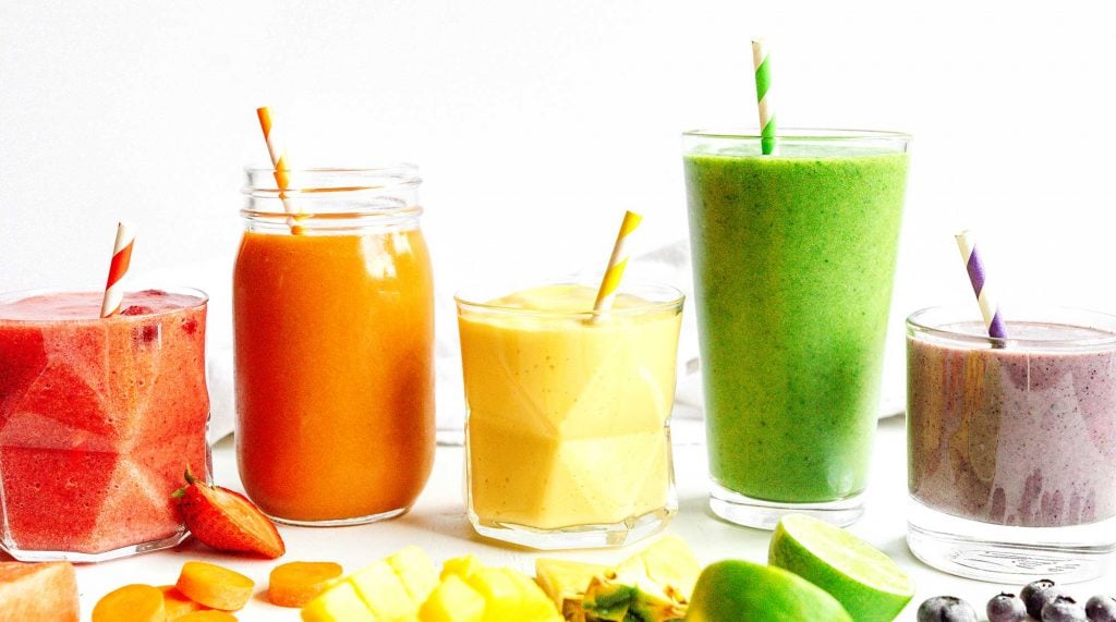 Different smoothies arranged in rainbow on white background
