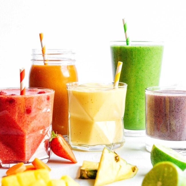 Different smoothies arranged in rainbow on white background