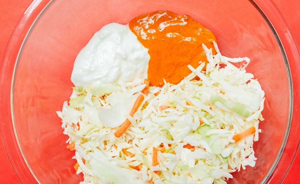 Kimchi mayo slaw in a glass bowl on a red background