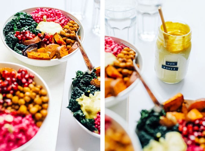 Buddha bowls with pink couscous, roasted chickpeas, sweet potato, kale, and yellow yumm sauce on a white background.