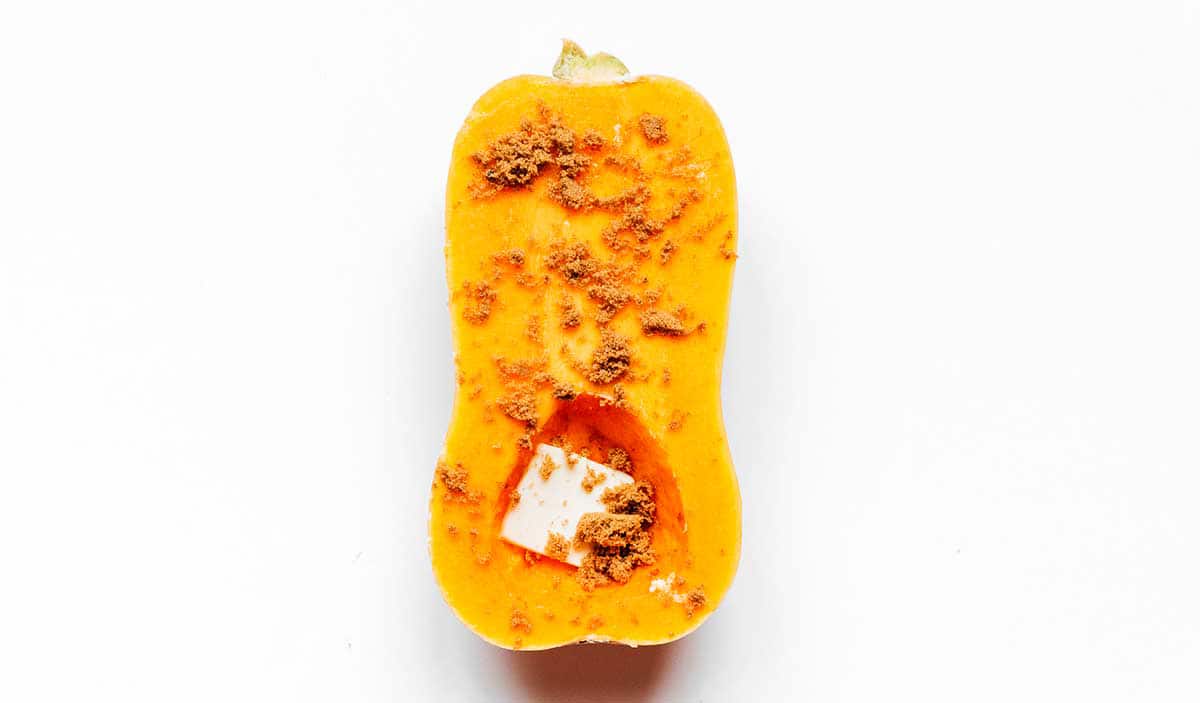 Half of a butternut squash coated with butter, brown sugar, and cayenne pepper