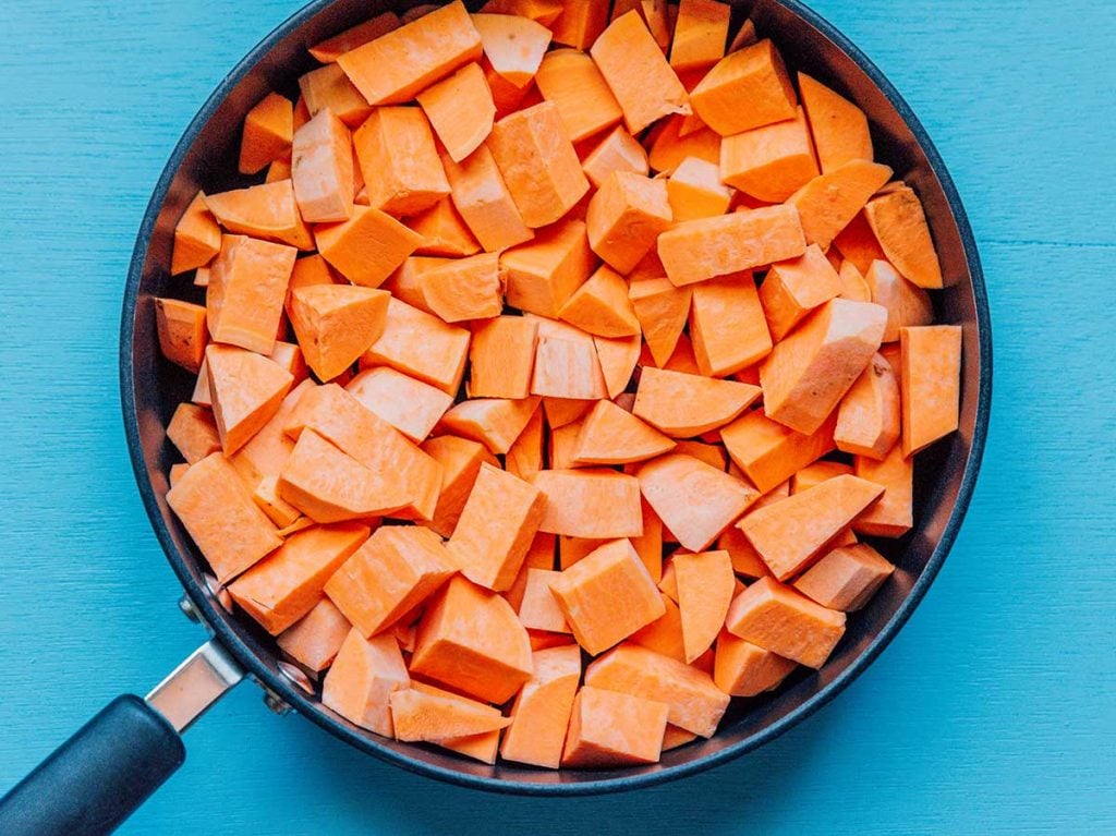 Cubed sweet potato in a pan on a blue background