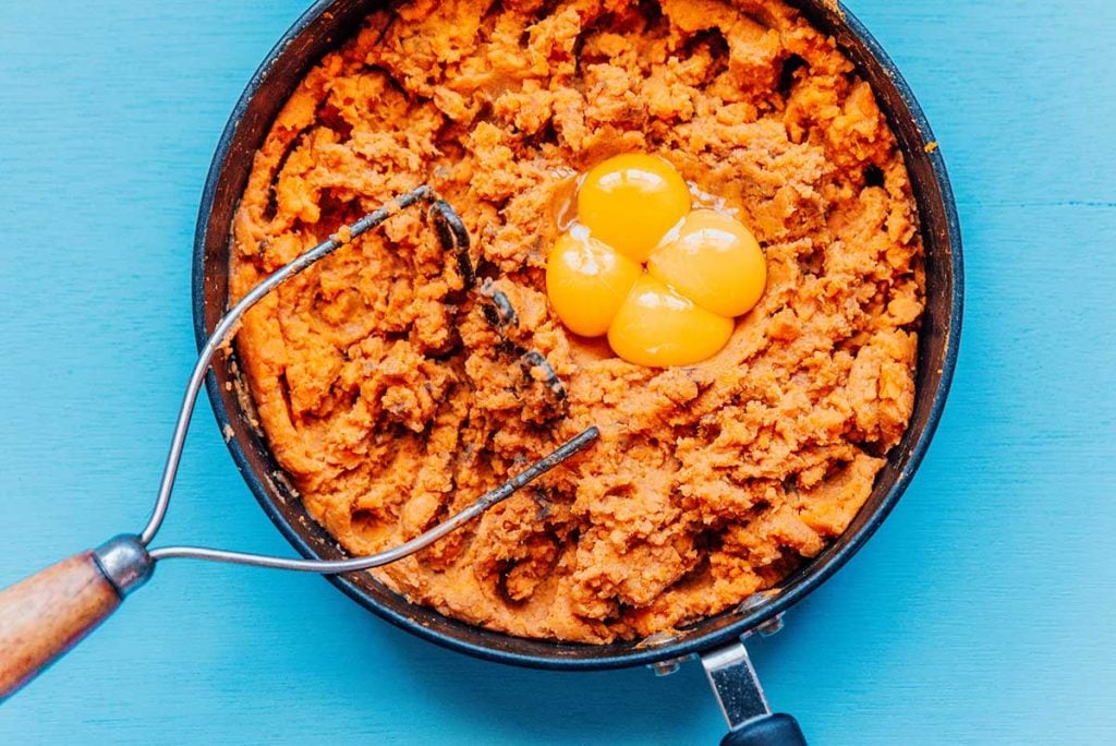 Mashed sweet potato in a pan on a blue background