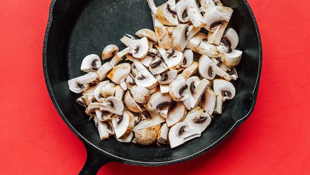 A cast iron skillet filled with sliced mushrooms