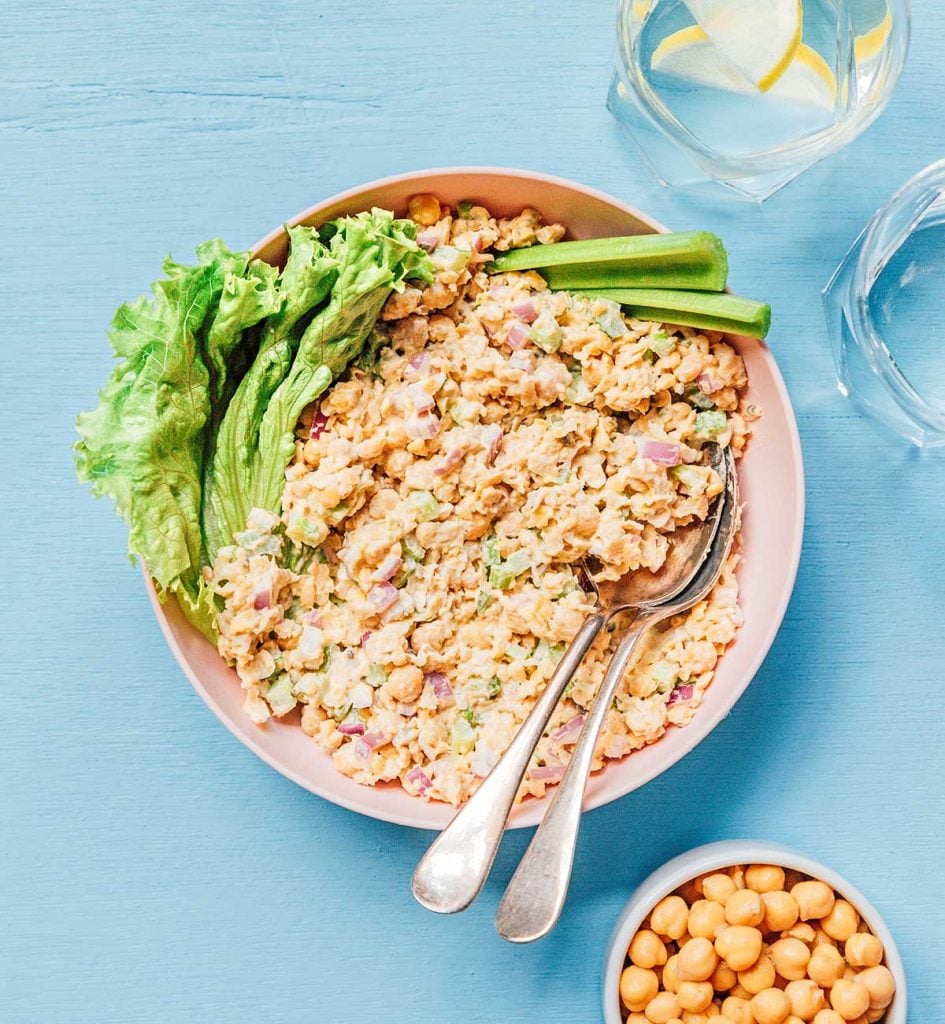 A bowl of chickpea tuna salad with two slices of celery and a piece of lettuce on top